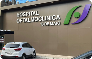 Fachada marrom de uma clínica, a edificação é térrea e mostra em letras garrafais metálicas os dizeres "Hospital Oftalmoclínica 13 de Maio" que fica em Fortaleza e faz parte da rede própria da Livsaúde