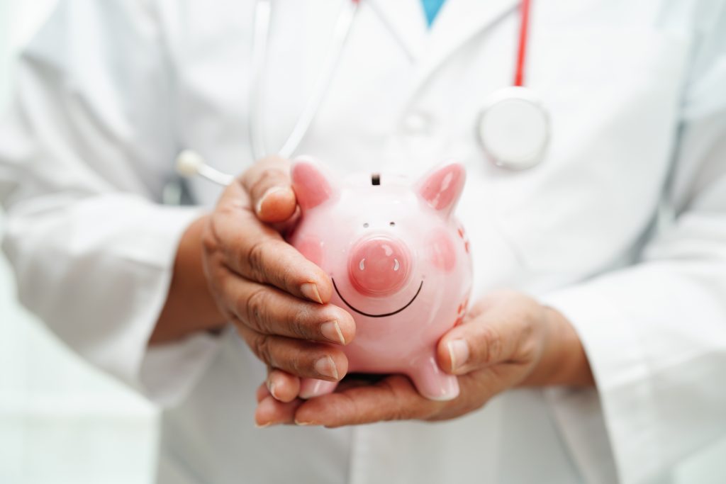 Médica segurando um cofrinho rosa, simbolizando economia e acessibilidade em planos de saúde acessíveis para toda a família.