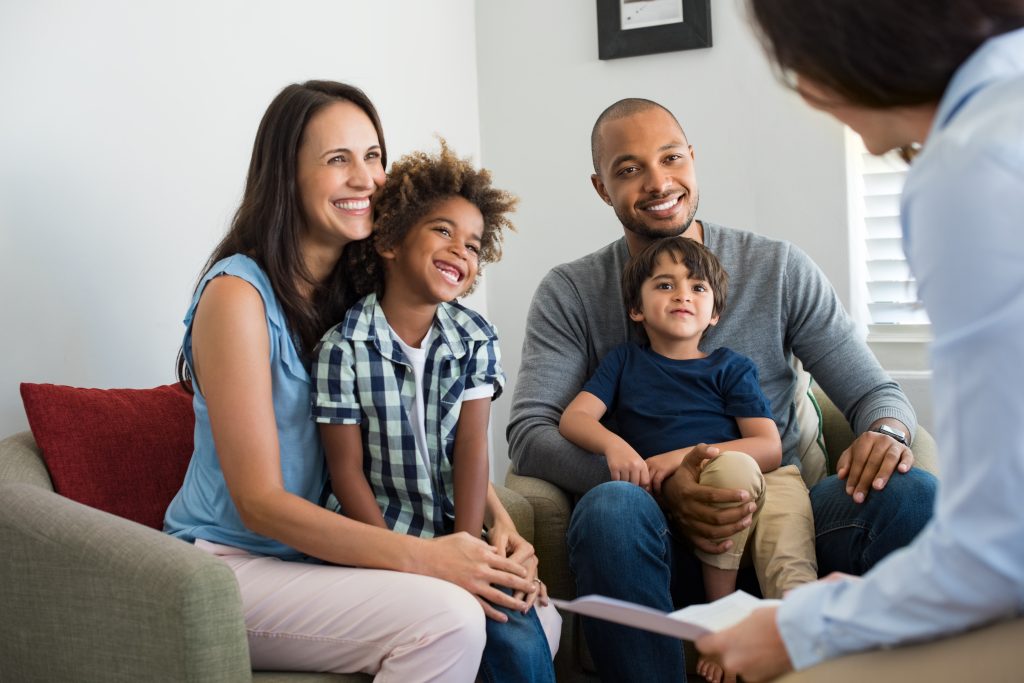 Família durante consulta médica com a mãe, o pai, duas crianças e a médica, ilustrando a importância do plano família para cuidados de saúde integrados.