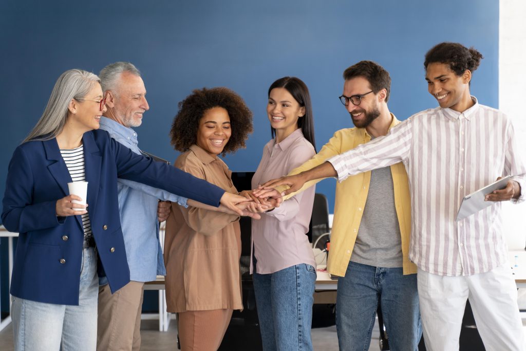 Imagem de colaboradores dando as mãos em sinal de união e cooperação, simbolizando a importância do trabalho em equipe e o apoio mútuo. A cena representa a valorização da saúde e bem-estar no ambiente corporativo, destacando o papel do plano de saúde para funcionários na promoção de um ambiente de trabalho saudável e colaborativo.