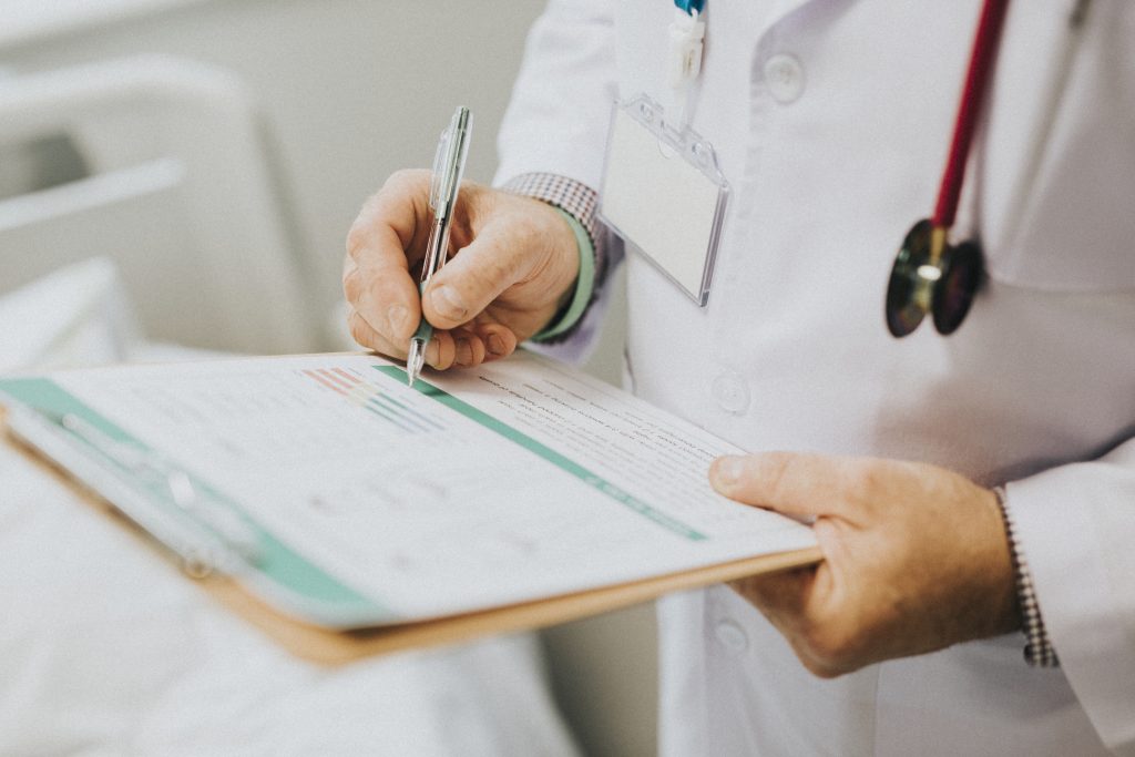 Médico preenchendo carteirinha de paciente, ilustrando a importância da cobertura médica no plano de saúde.