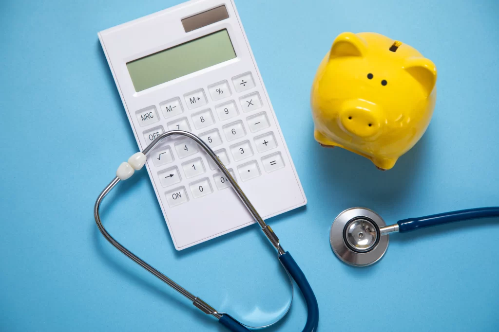 Calculadora, estetoscópio médico e cofrinho amarelo simbolizando o que considerar na tabela de preço plano de saúde.