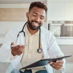 Médico sorridente analisando documentos, simbolizando a importância do plano de saúde para médico.